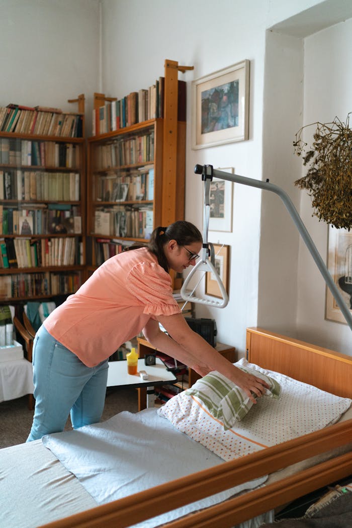 A caregiver adjusts bedding in a cozy home library setting in Prague.